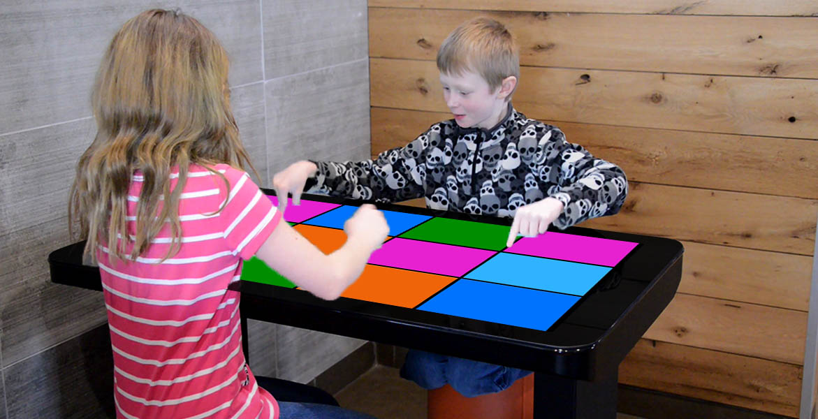 2 kids playing a touchscreen tabletop game on Kidzpace Interactive Play Table the Family Entertainment Table while waiting to eat at a McDonald's restaurant